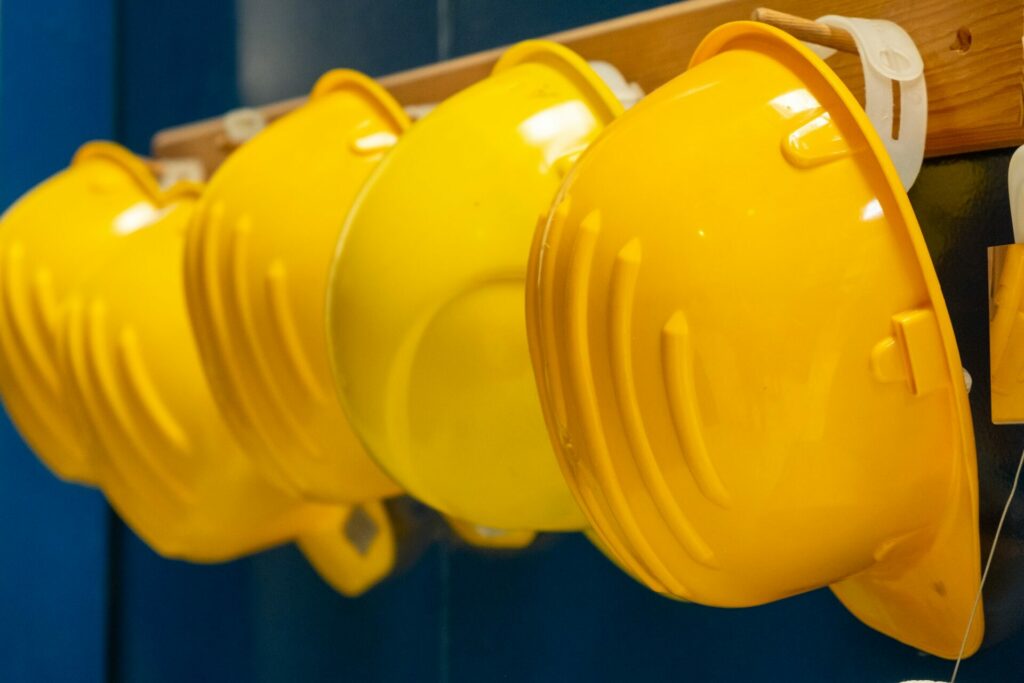 Yellow protective helmets hang on wooden bar at plant