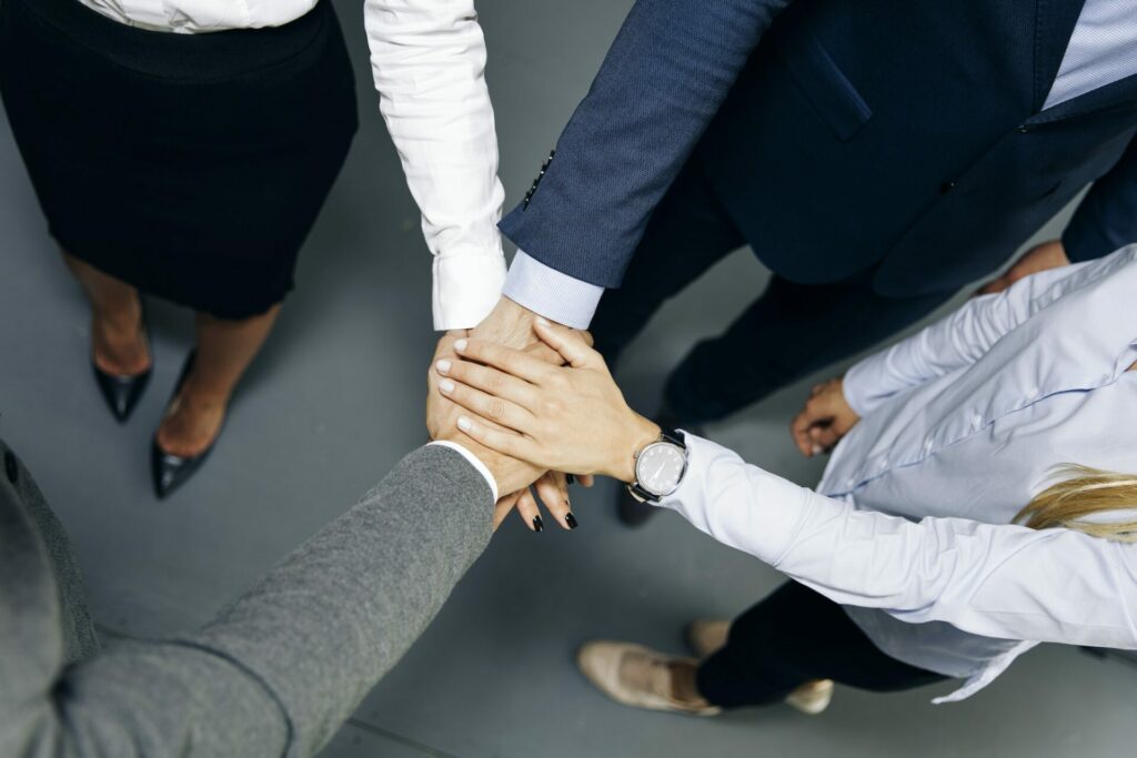 Young coworkers putting hands together as symbol of unity in the office